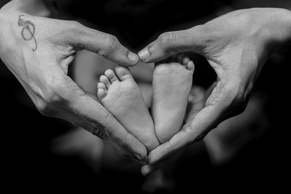 a couple of hands holding a baby's feet