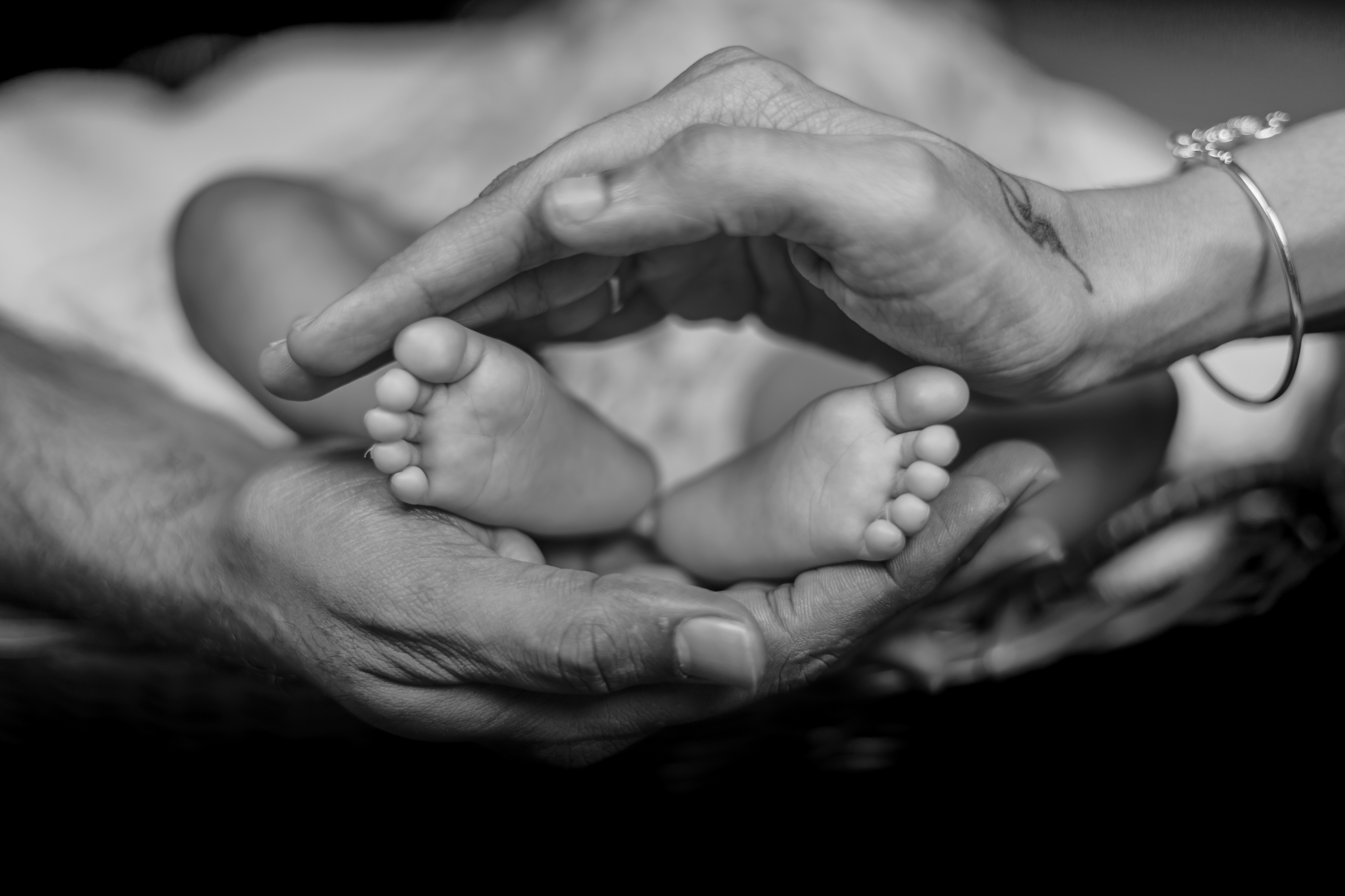 a black and white photo of a person holding a baby's feet
