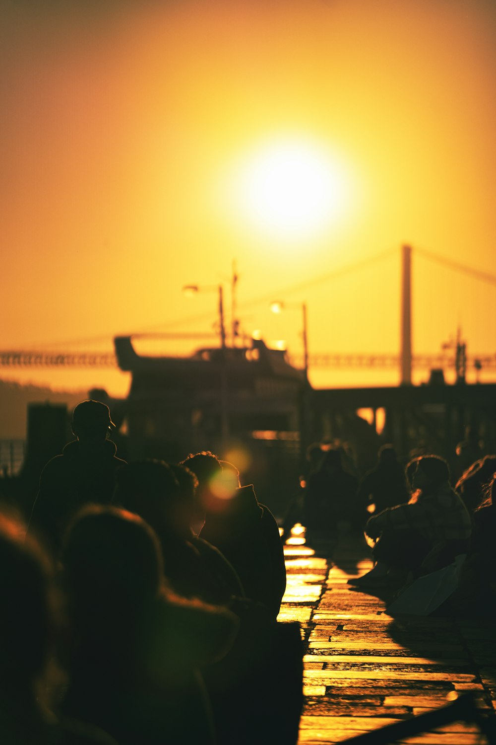 a group of people sitting on a dock watching the sun go down