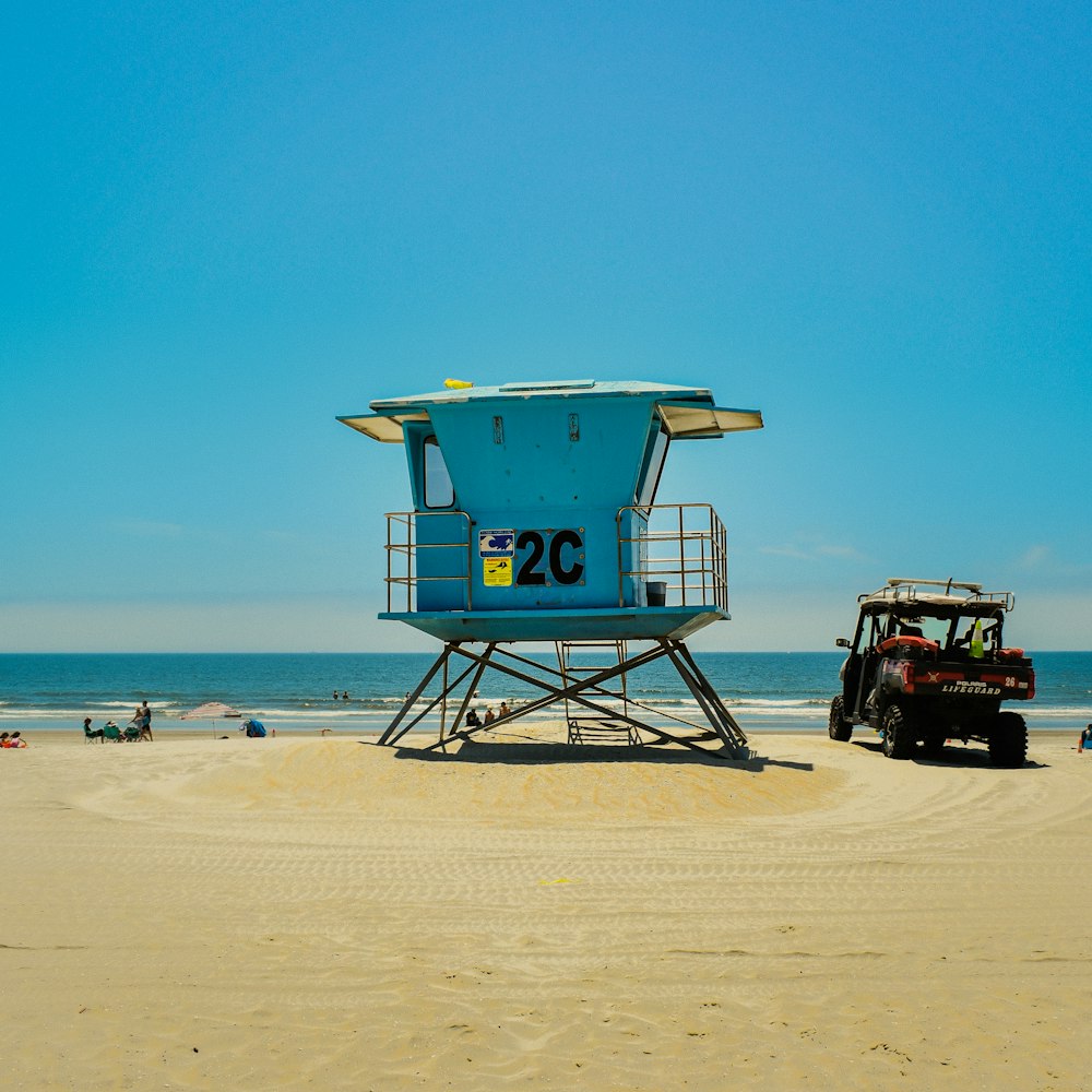 a lifeguard tower on the beach with a jeep parked in front of it