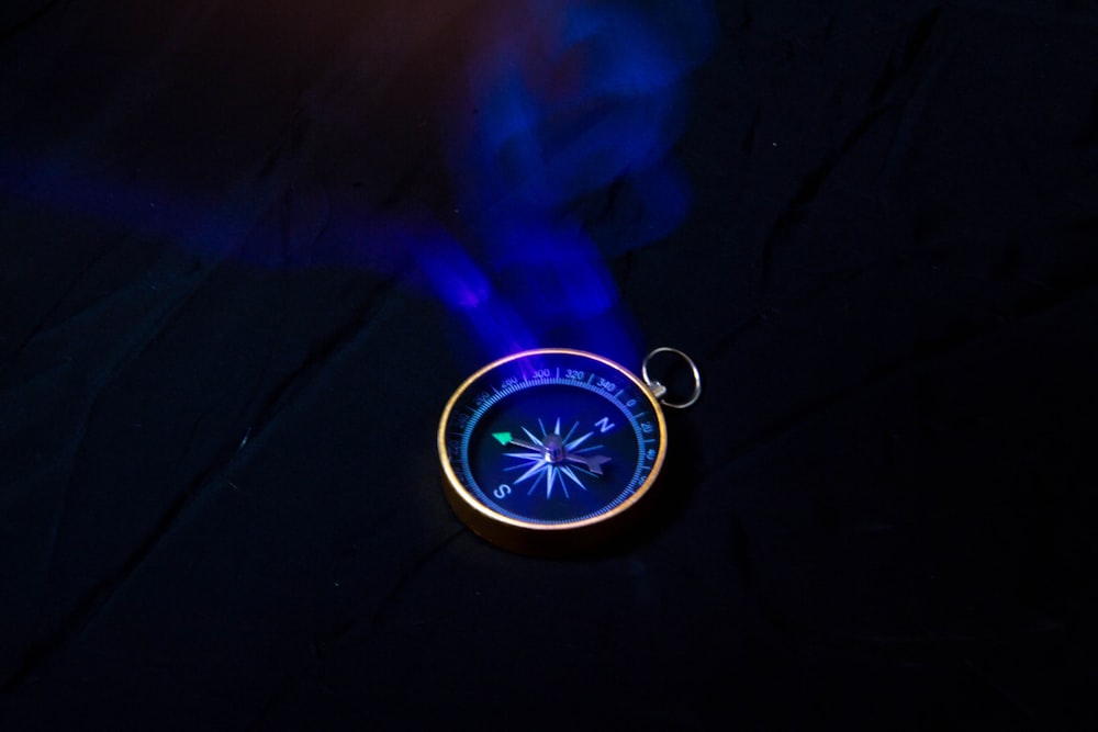 a compass keychain with a blue light coming out of it