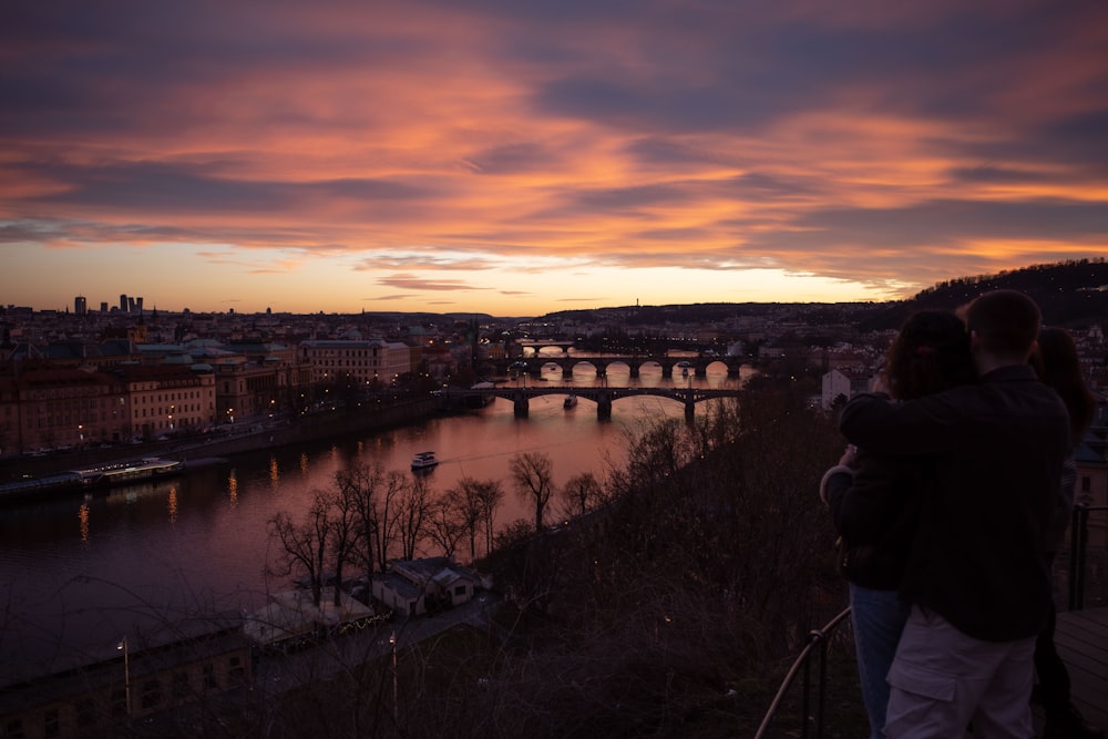 a couple of people standing next to each other near a river