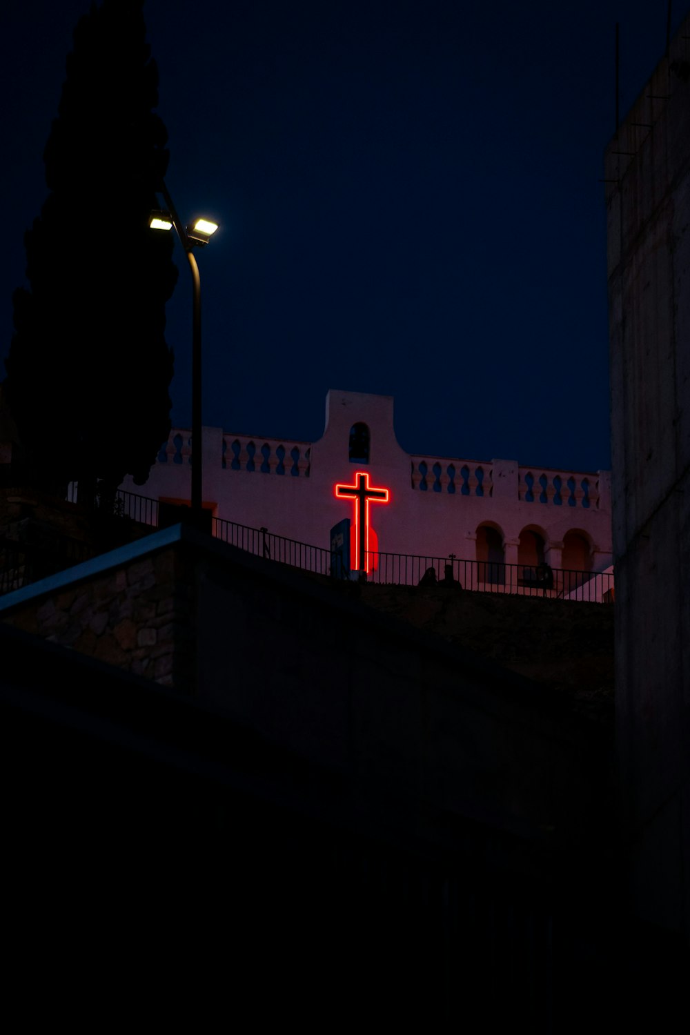 a red cross lit up on a building at night