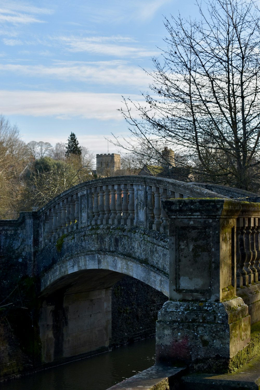 a stone bridge over a small river in a park