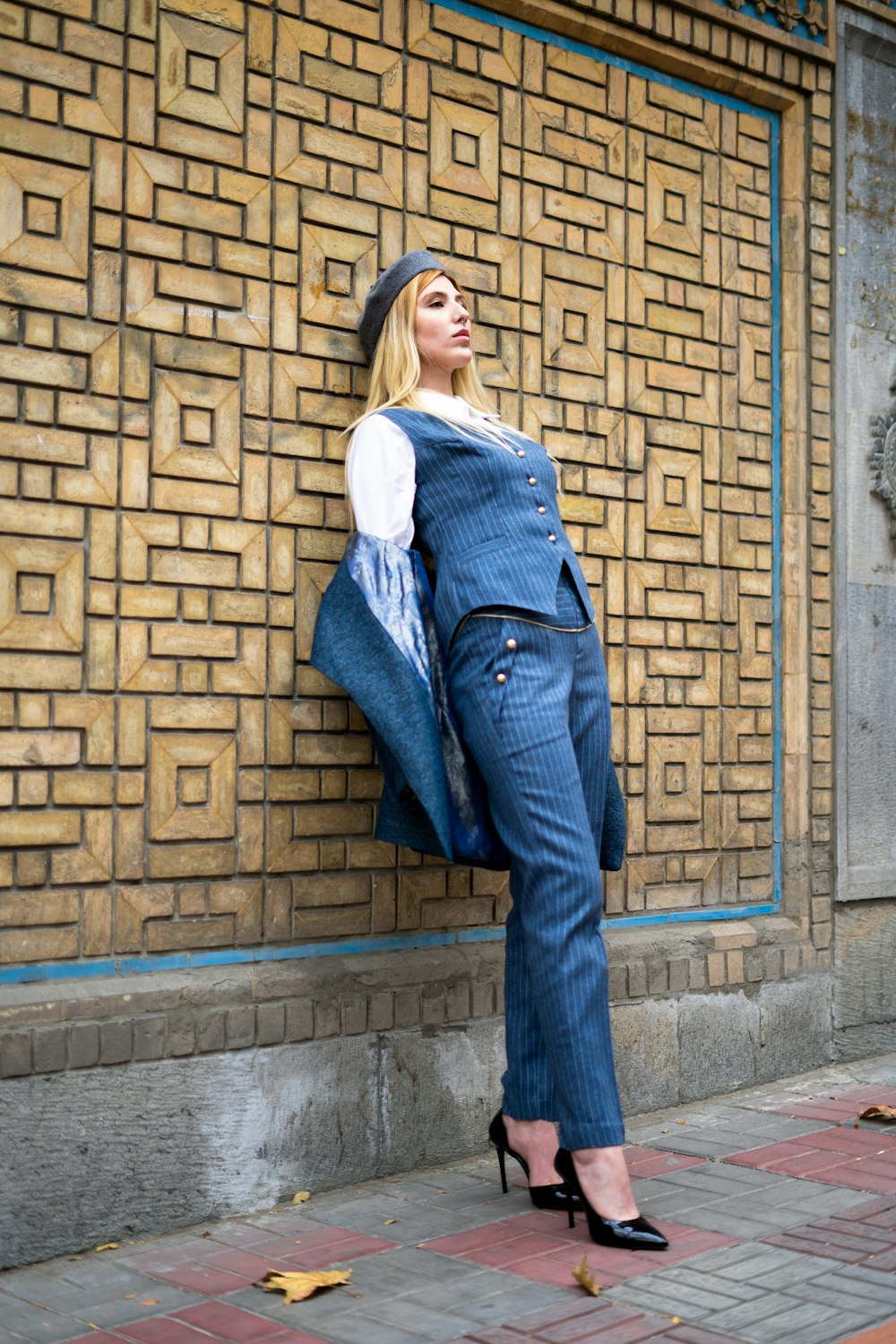 a woman leaning against a wall with her hand on her hip