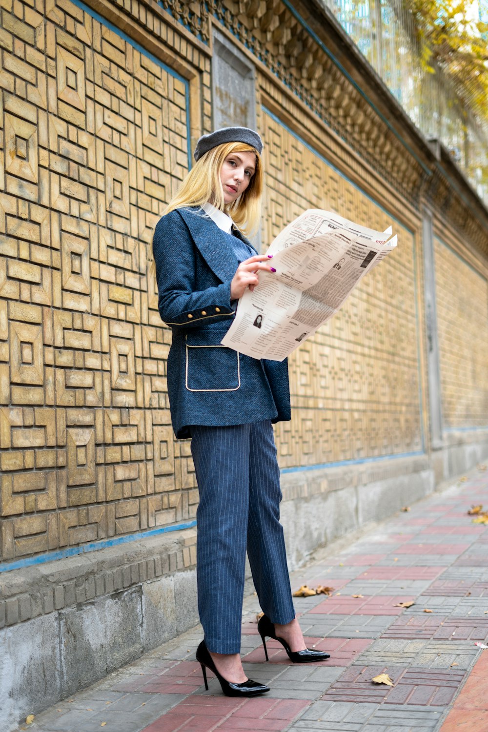 a woman in a suit and hat is reading a newspaper