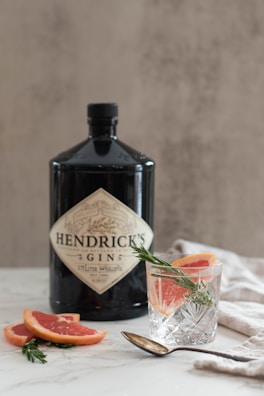 a bottle of hendrick's gin next to a glass of blood orange
