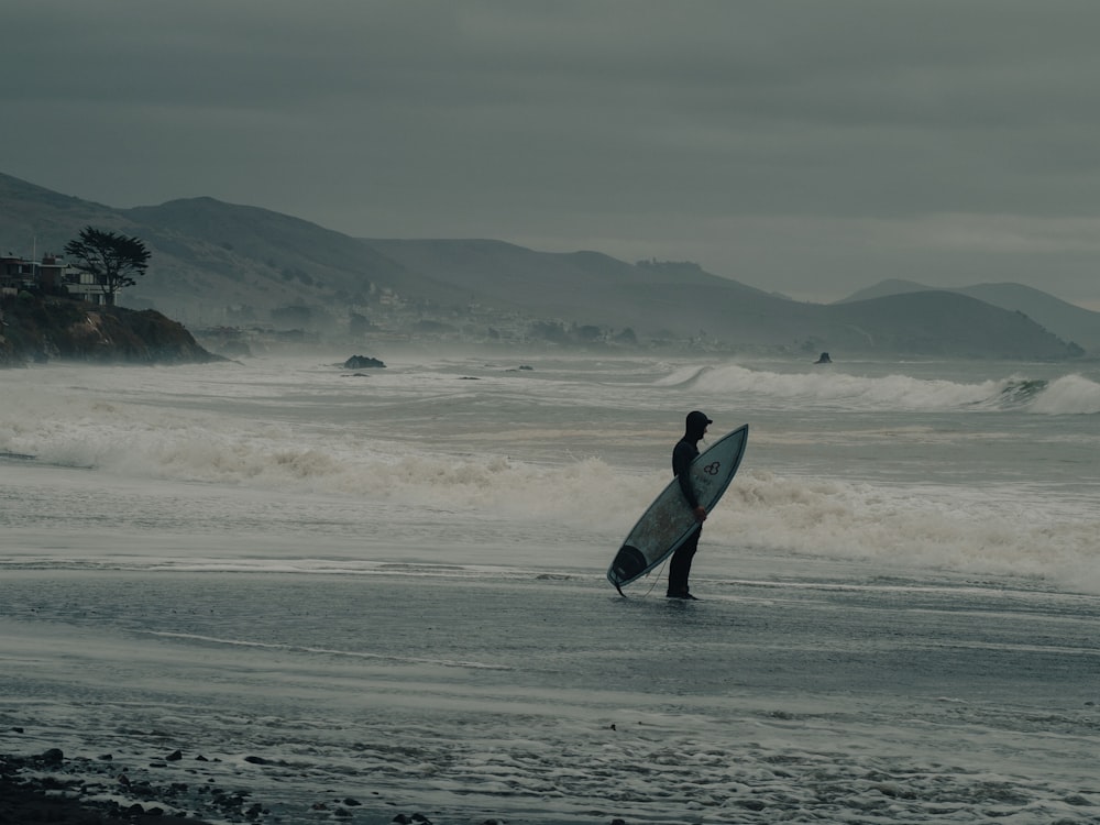 a person holding a surfboard on a wet beach