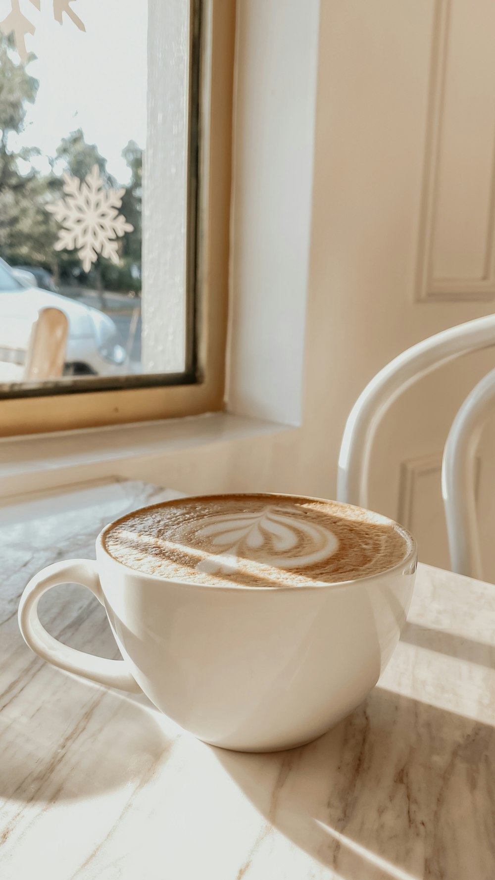 a cappuccino sits on a table in front of a window