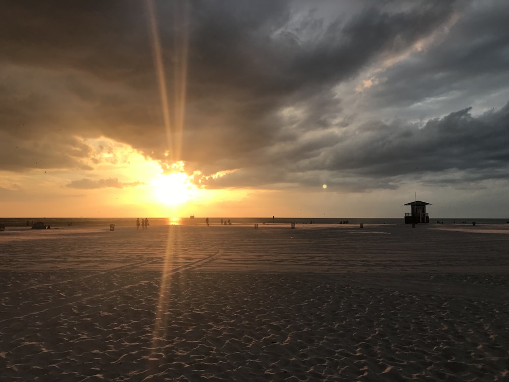 the sun is setting over the beach with people on it