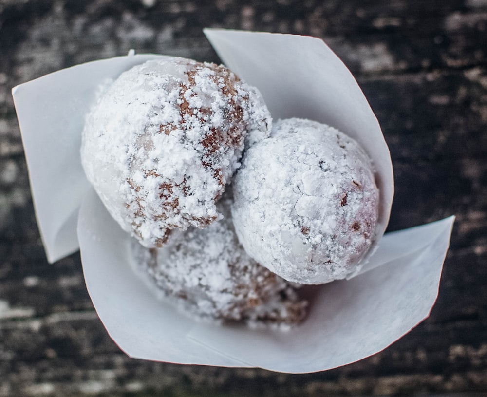 two powdered donuts sitting on top of a paper wrapper