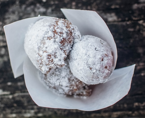 Two powdered donuts sitting on top of a paper wrapper