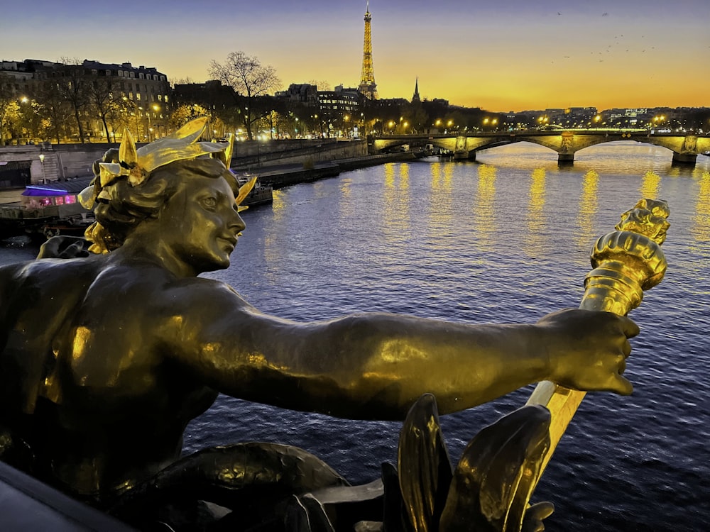 a statue of a man holding a torch in front of a river