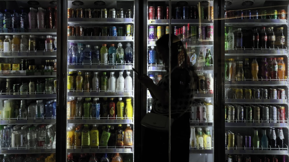 a woman standing in front of a refrigerator filled with drinks
