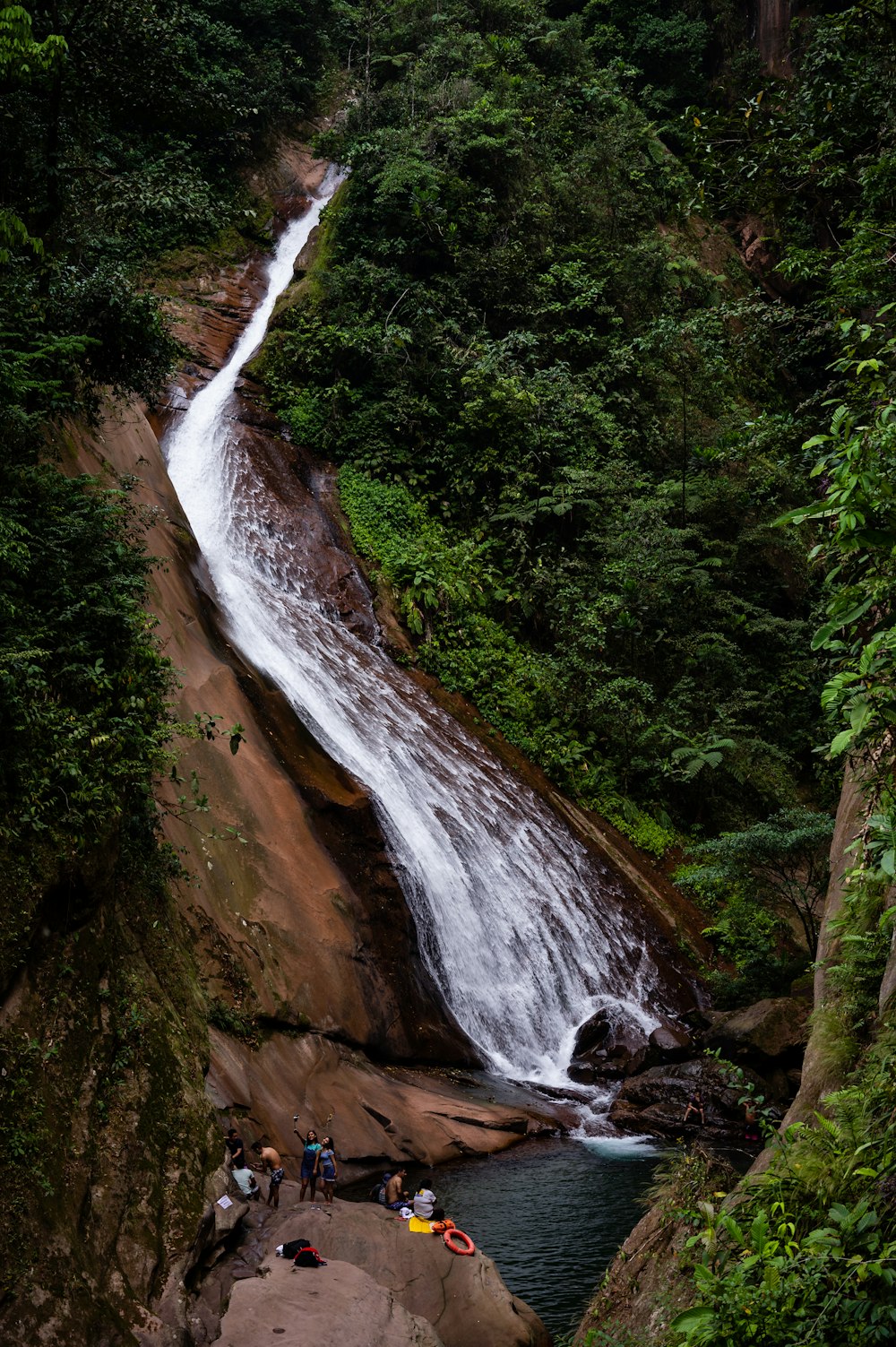 a group of people standing next to a waterfall