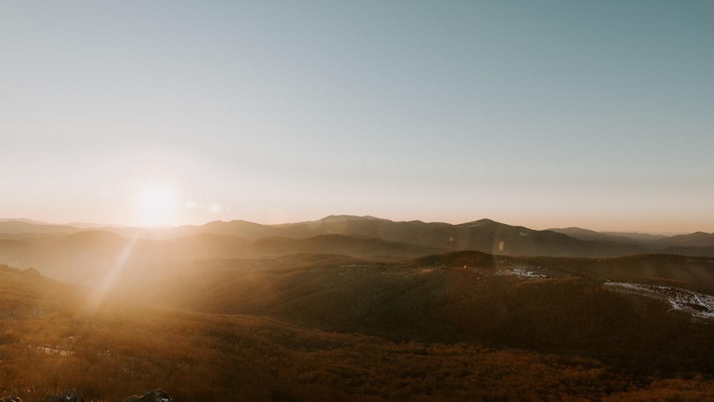 the sun is setting over a mountain range