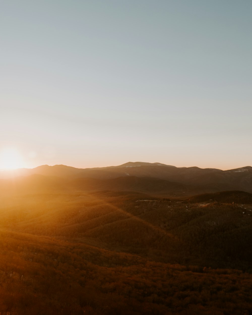 the sun is setting over a mountain range