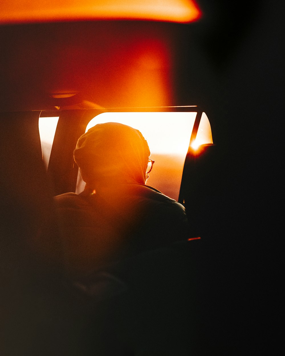 a person sitting in a car with the sun shining through the window