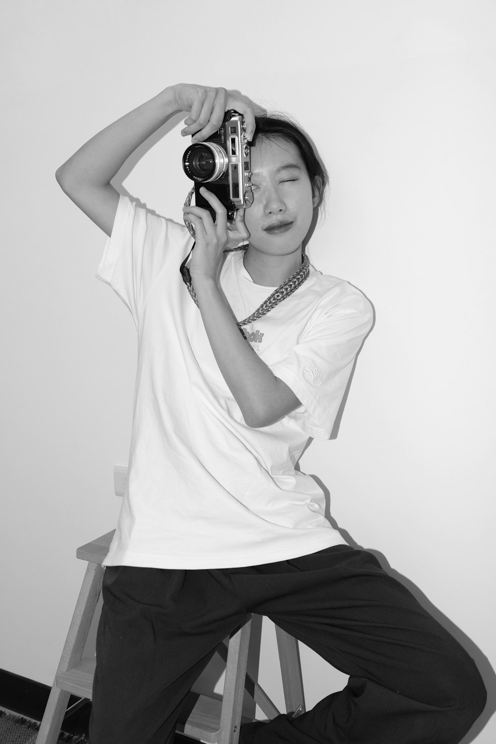 a woman sitting on a stool holding a camera