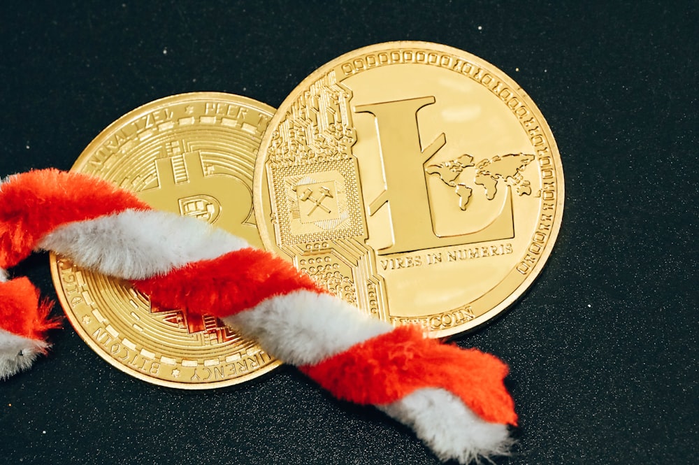 a red and white candy cane laying on top of a gold coin