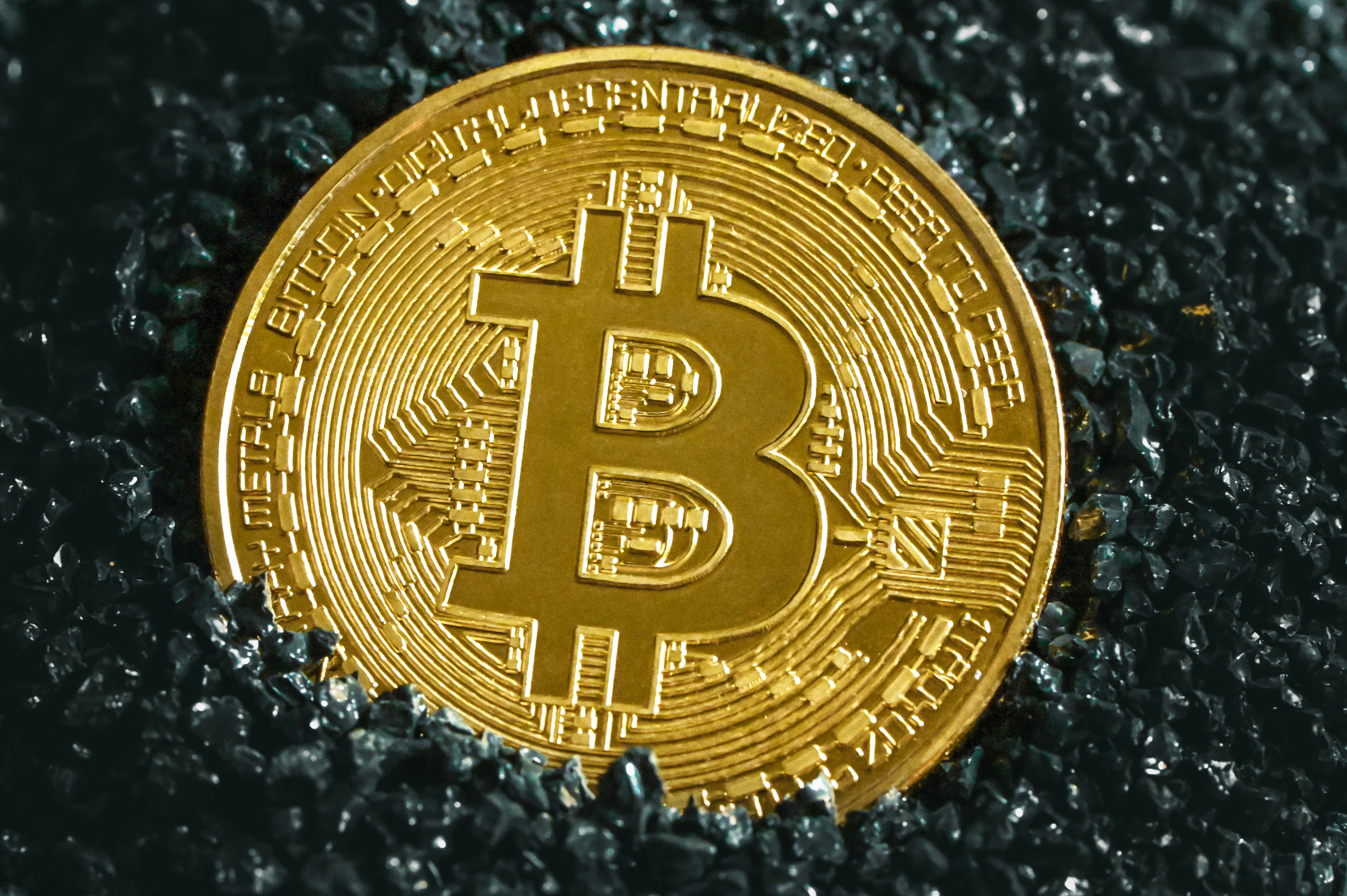 A gold Bitcoin is shining in the dark stones