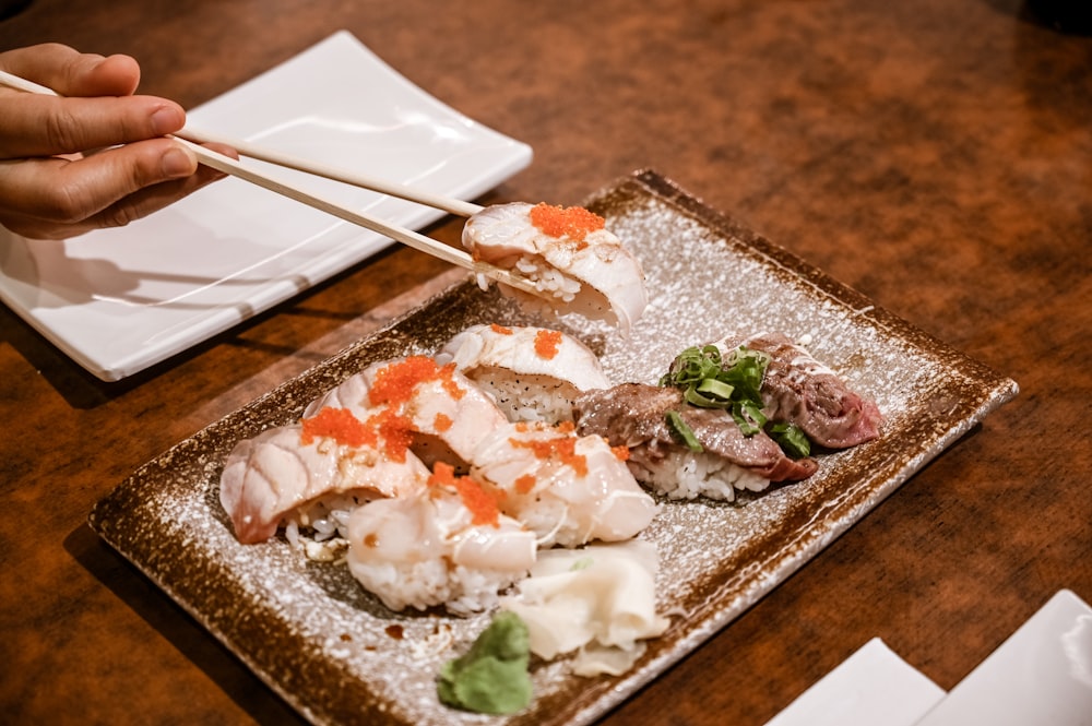 a person holding chopsticks over a plate of food