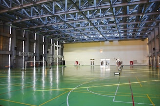an indoor basketball court with green and yellow lines