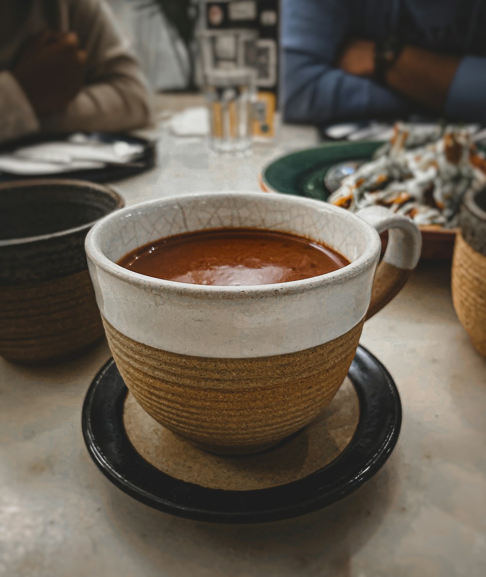 a bowl of soup sitting on top of a black plate