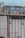 Several large industrial cooling fans are mounted on top of a structure with metal railings and numerous pipes of varying sizes. The fans are enclosed in a horizontal metal frame, and the structure appears to be part of a larger industrial facility. The surface shows signs of wear and weathering.