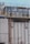 Several large industrial cooling fans are mounted on top of a structure with metal railings and numerous pipes of varying sizes. The fans are enclosed in a horizontal metal frame, and the structure appears to be part of a larger industrial facility. The surface shows signs of wear and weathering.