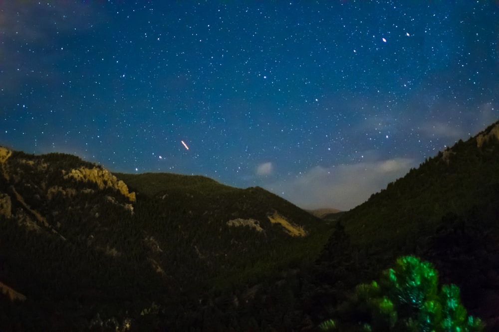 the night sky with stars above a mountain range