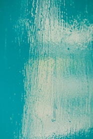 Elegant wall finish with a smooth, matte surface in muted aquamarine tones accented by warm copper highlights.