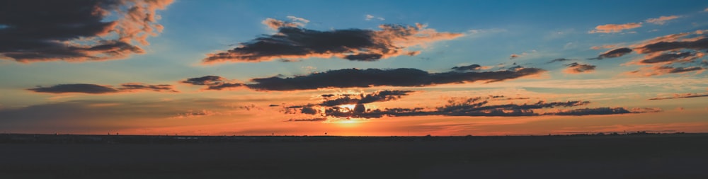 the sun is setting over the horizon of a field