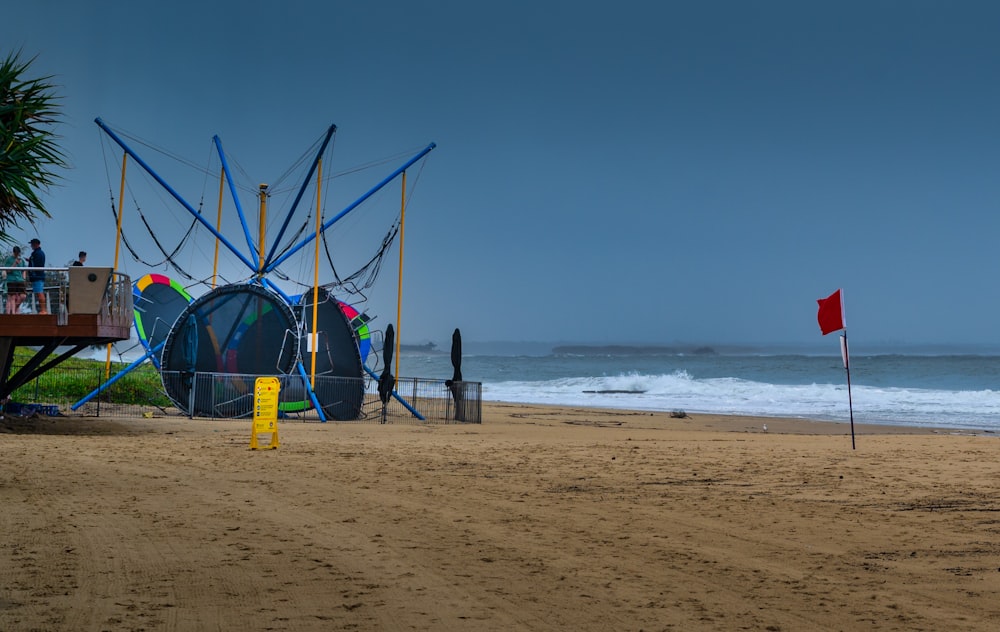 a beach with a blue tent and a red flag