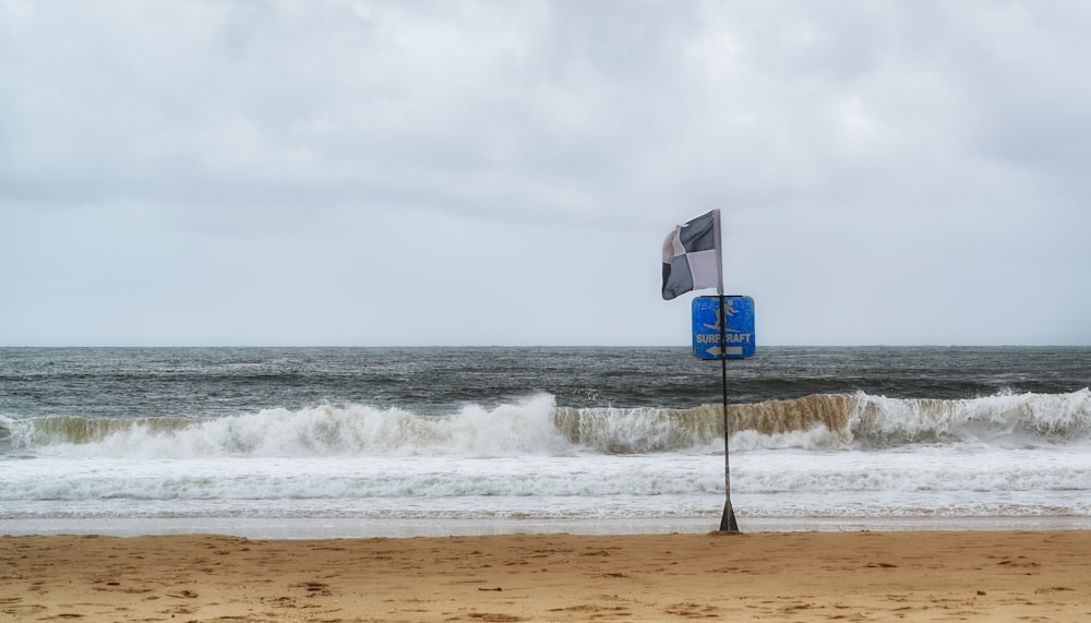 a blue and white sign sitting on top of a sandy beach