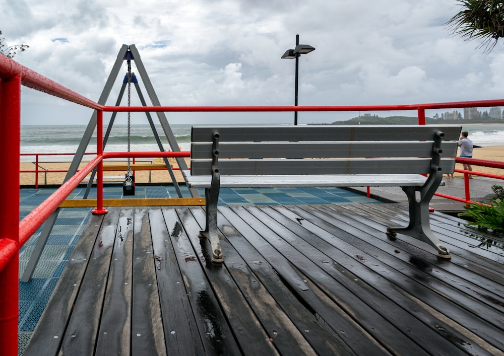 a bench sitting on top of a wooden deck next to the ocean