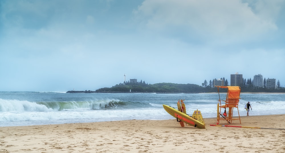 a yellow lifeguard chair sitting on top of a sandy beach