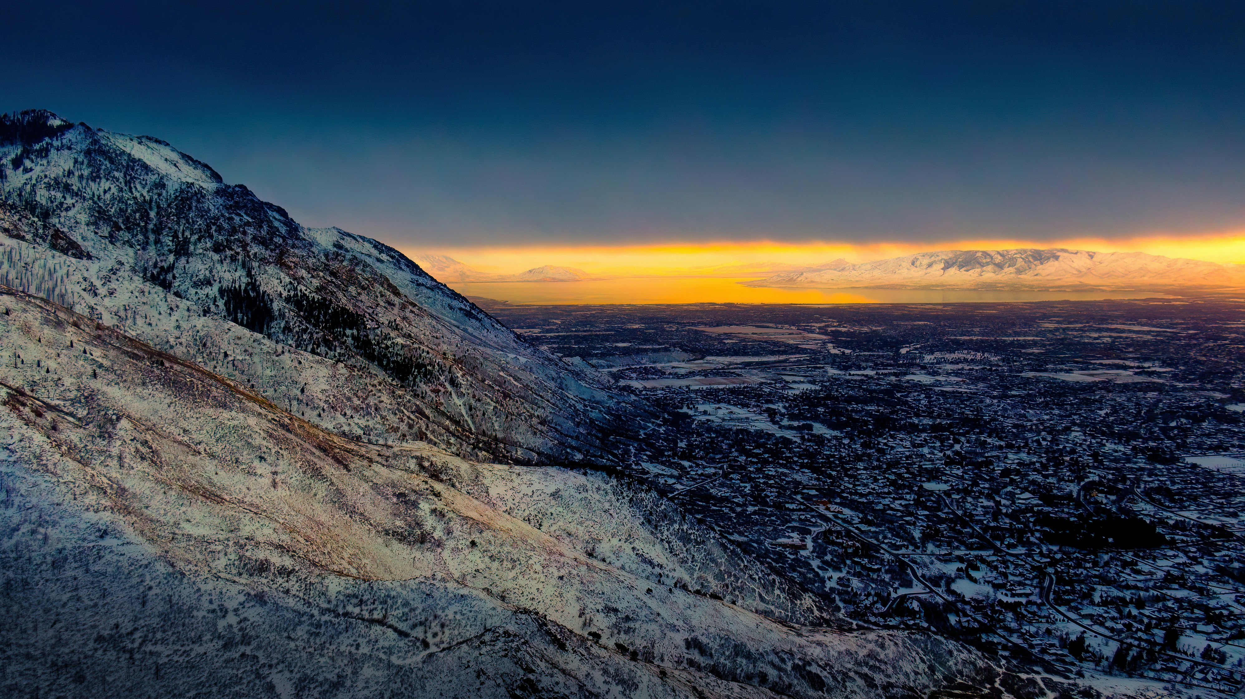 a view of a snowy mountain with a sunset in the background, Sunset over Utah County with a low cloud layer