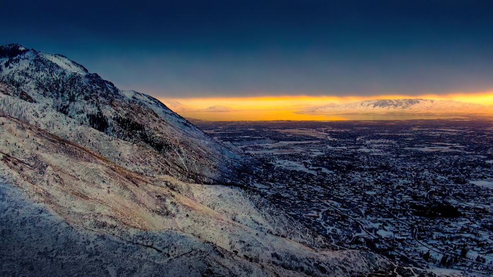 Blick auf einen verschneiten Berg mit Sonnenuntergang im Hintergrund