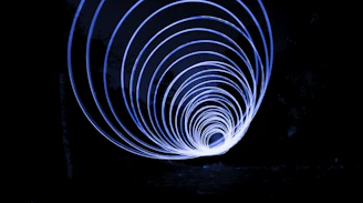 Abstract glowing circular lens with electric-blue light trails sweeping over a dark horizon.