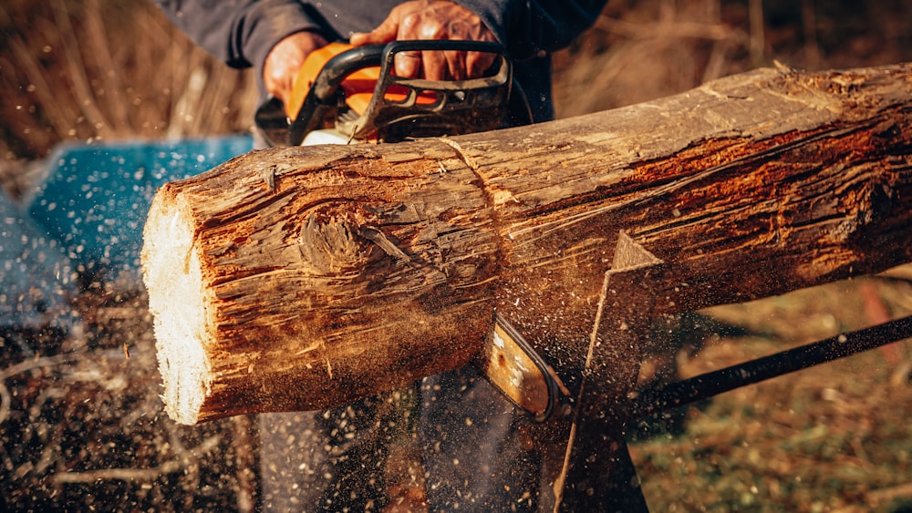 a man using a chainsaw to cut a log