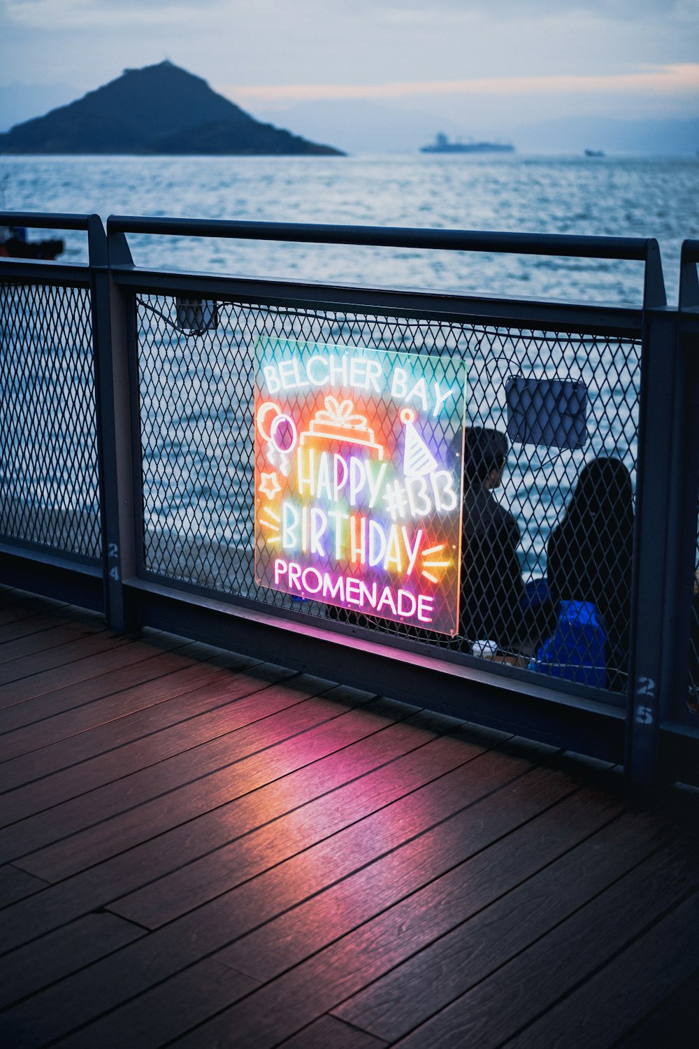 a neon sign on the side of a metal fence