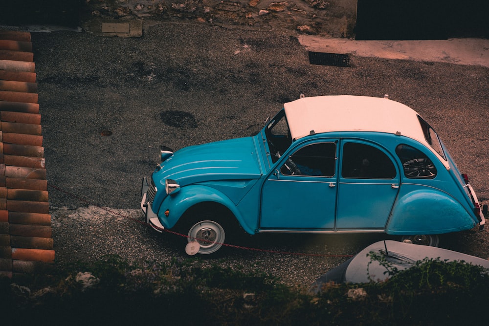 an old blue car parked in a parking lot