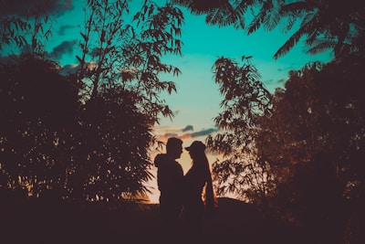 A romantic sunset scene with silhouettes of the couple framed by exotic flowers.