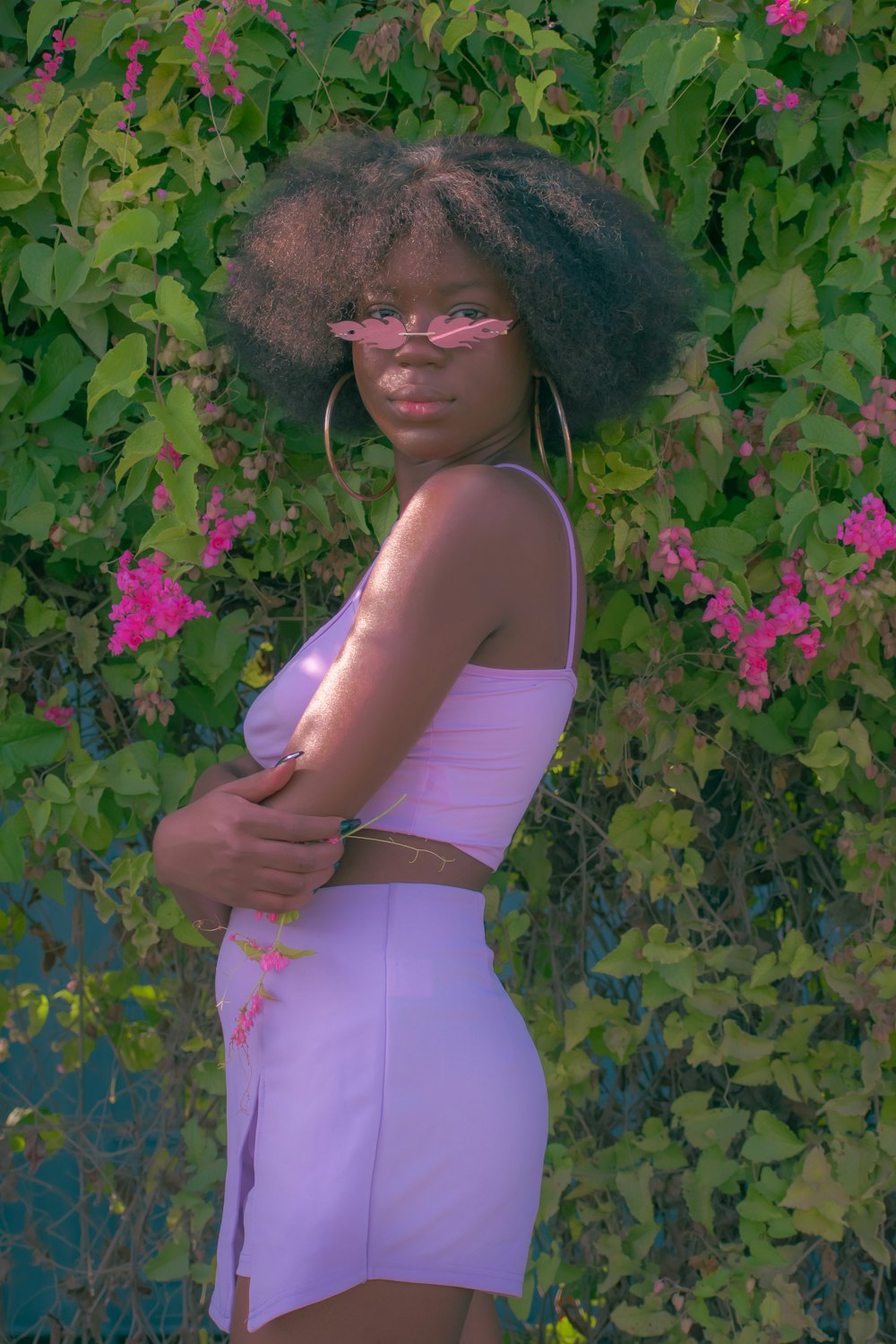 a woman with an afro standing in front of flowers