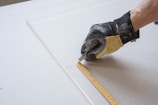 a person measuring a piece of paper with a tape