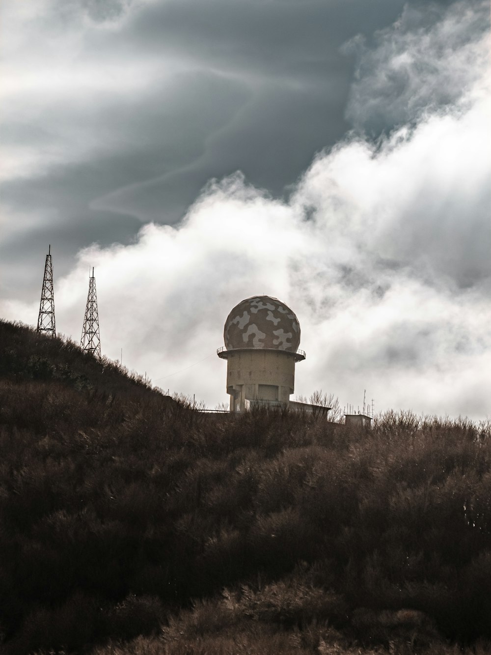 a satellite dish on top of a hill under a cloudy sky