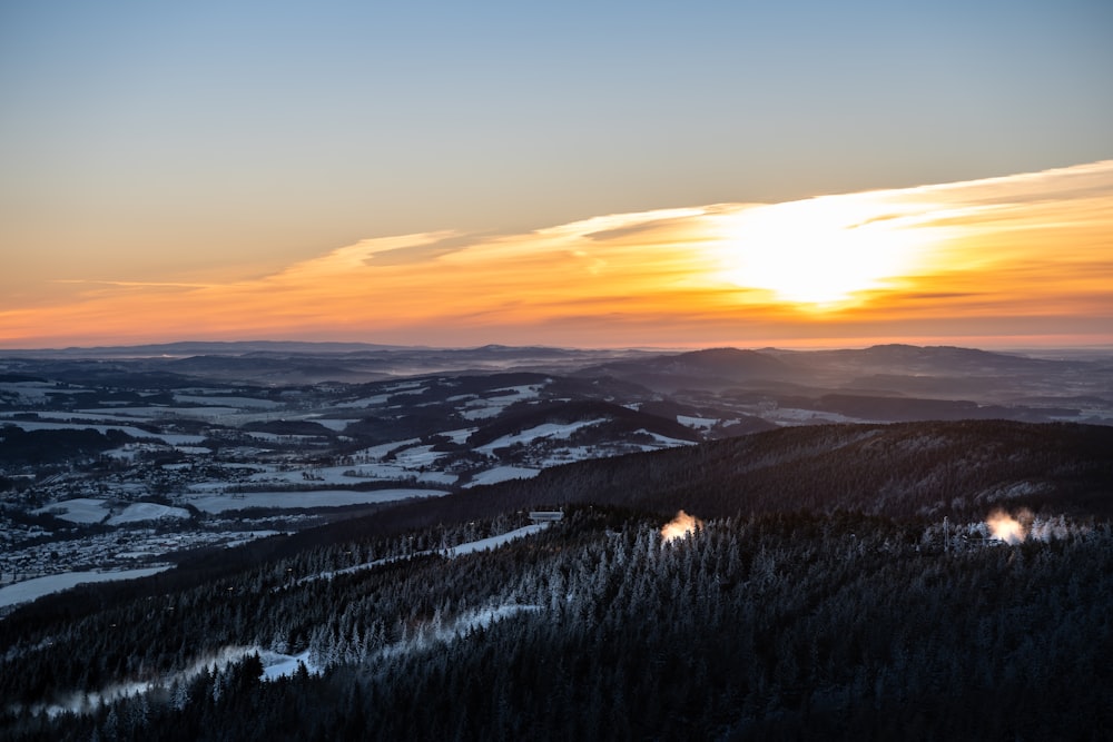 the sun is setting over a snowy mountain range