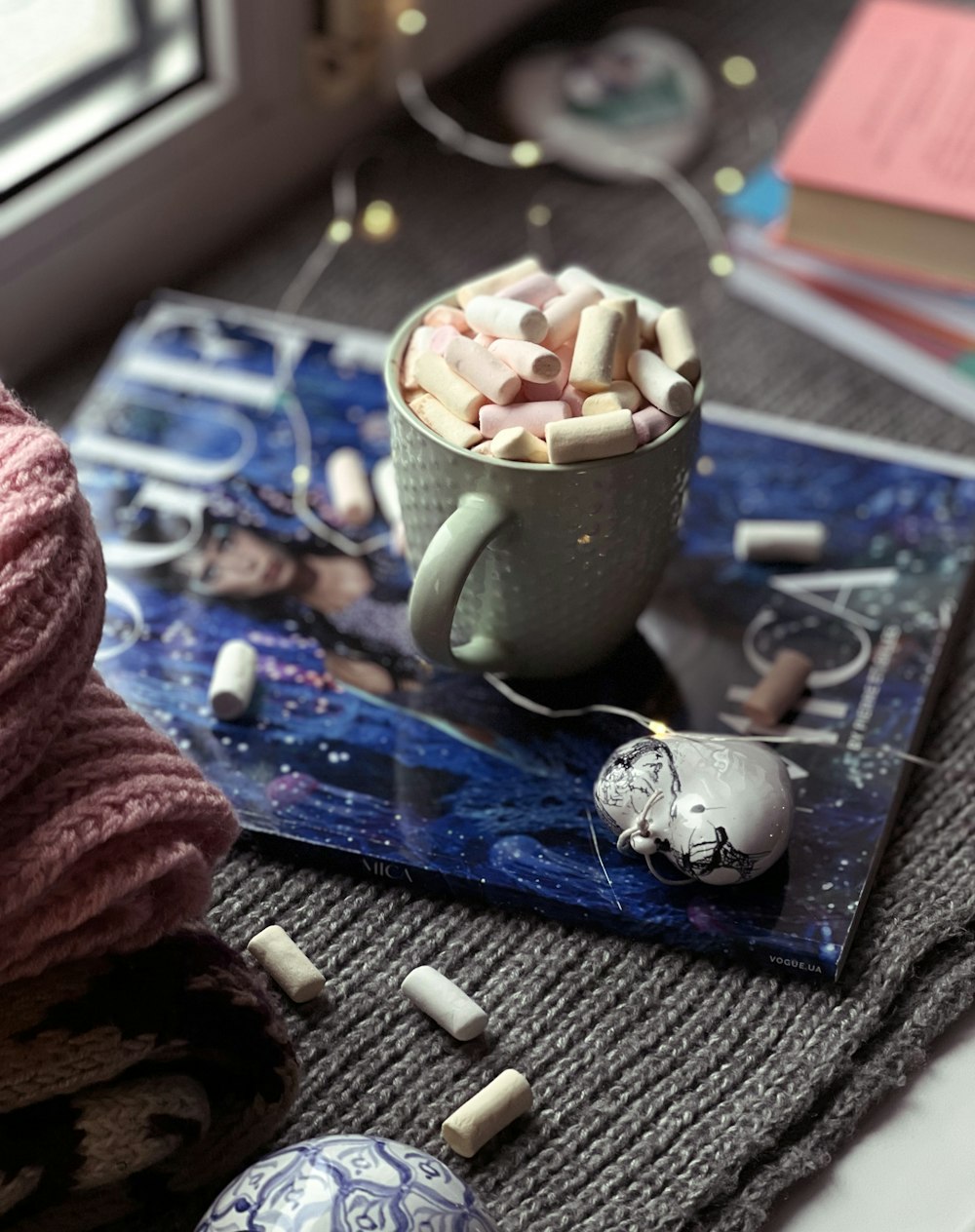 a cup of marshmallows on a tray next to a window