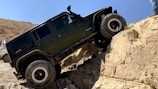 A powerful off-road SUV climbing rocky terrain in the Texas hill country.